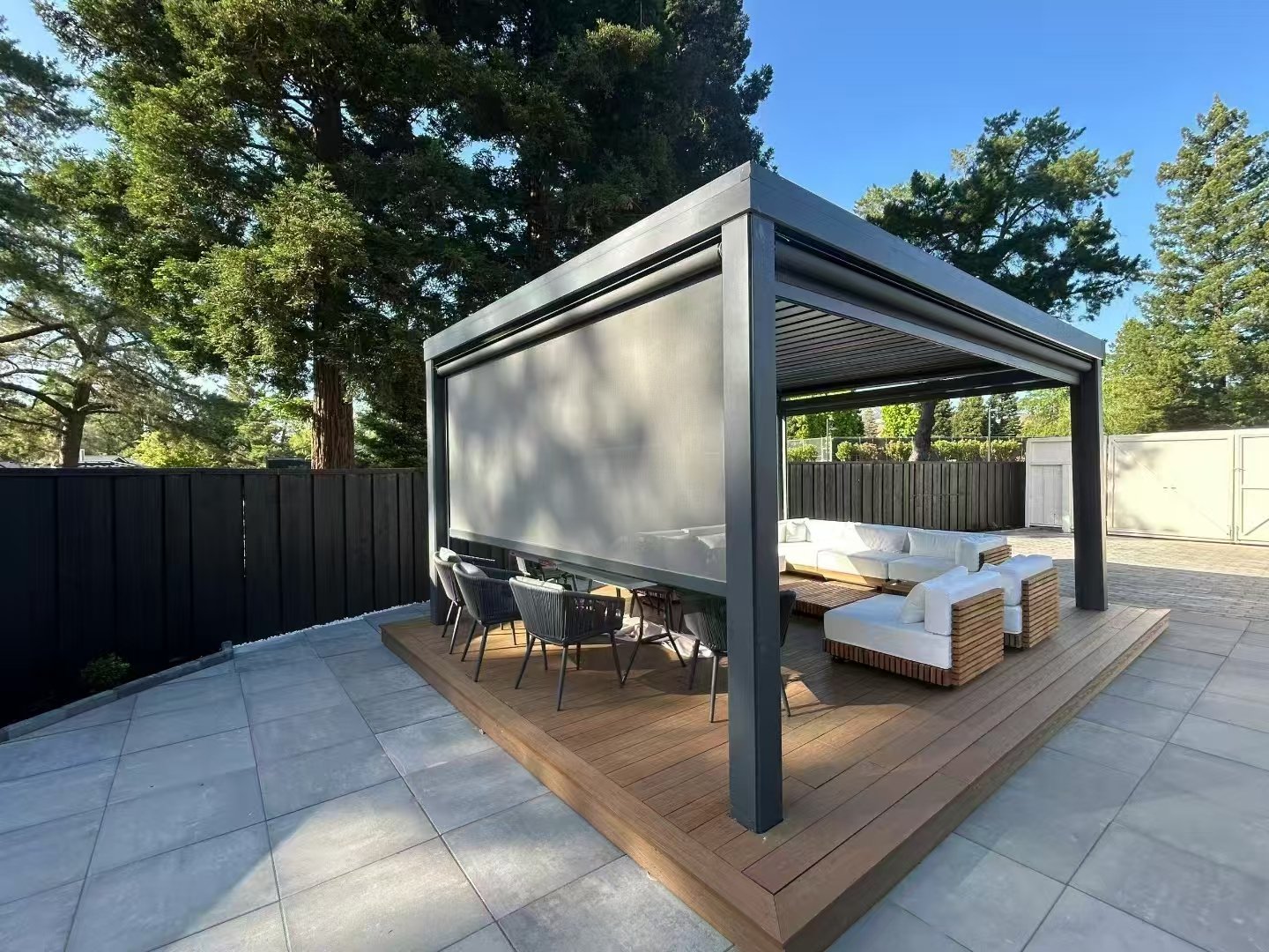 Freestanding aluminum louvered pergola with a retractable windproof side screen installed over an outdoor patio seating area