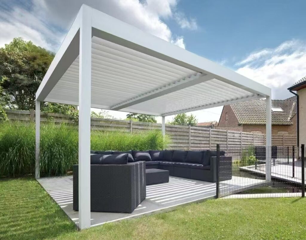 White freestanding aluminum louvered pergola with adjustable roof slats installed over a residential garden lounge area