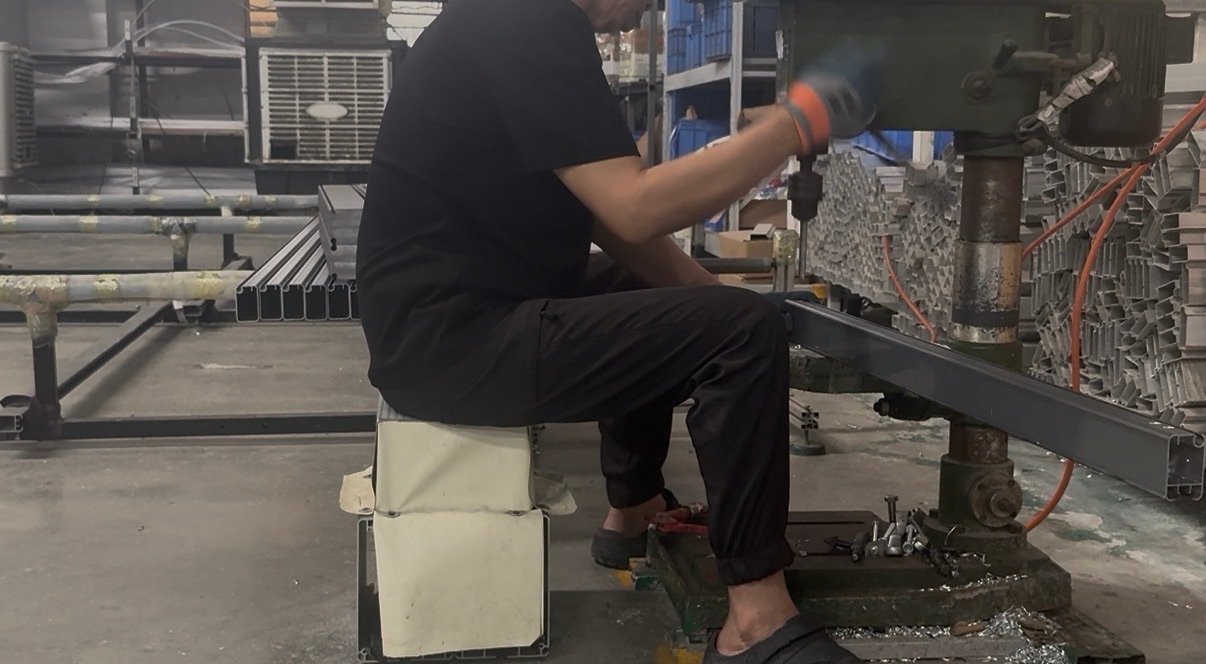 Factory worker drilling and machining a dark finished aluminum profile