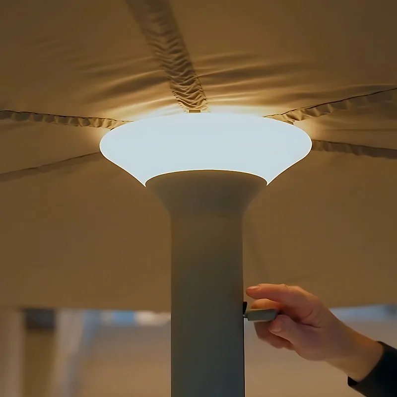 Close-up of a Milan patio umbrella with an integrated LED center light and manual crank operating handle