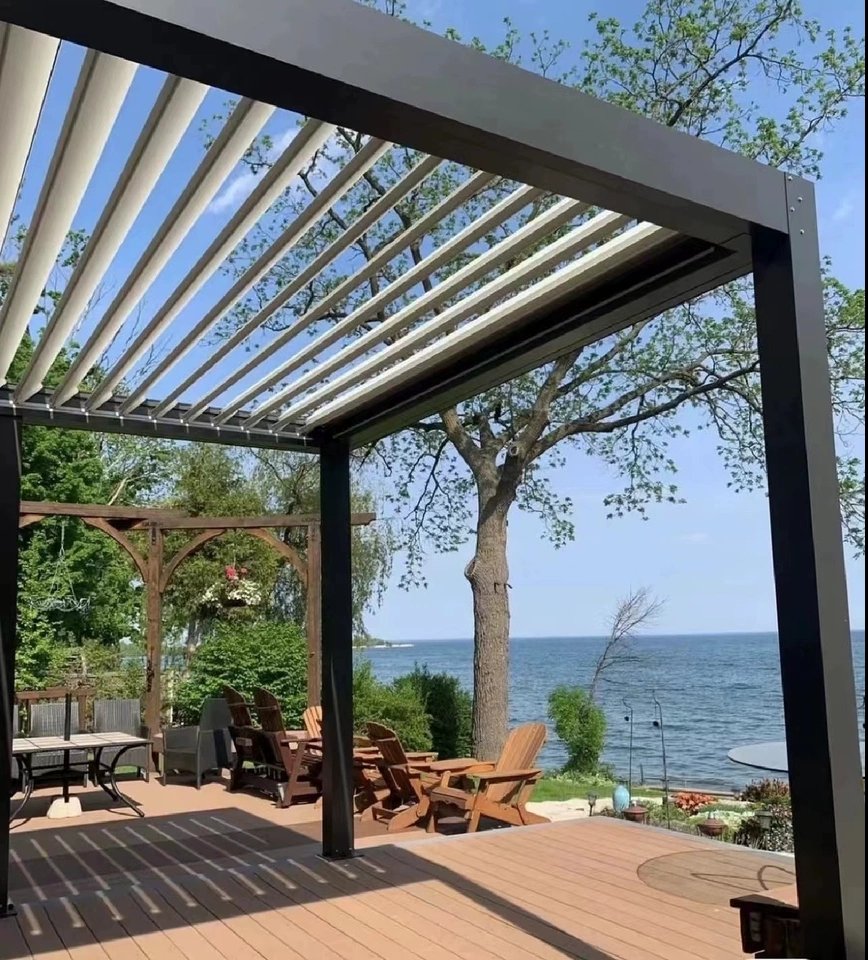 Black aluminum bioclimatic pergola with adjustable white louvers installed on a lakeside outdoor deck